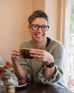 Photo of Sharon Worth smiling and drinking coffee.
